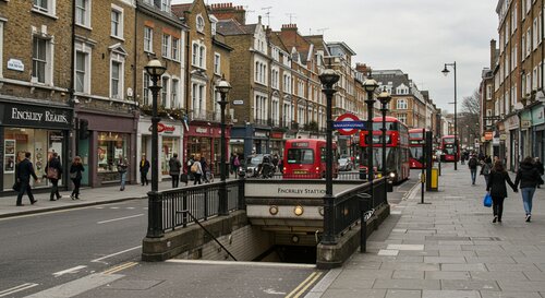 Finchley Road London street view with Underground station entrance and typical London red buses and black cabs