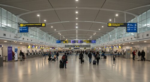Luton Airport interior showing check-in desks, passengers with luggage, and modern terminal facilities with clear directional signage